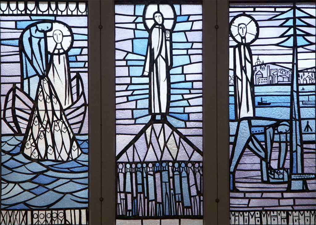 Stained-glass triptych depicting haloed figures by the sea, on a mount, and near a village, rendered in cool blue and purple tones.