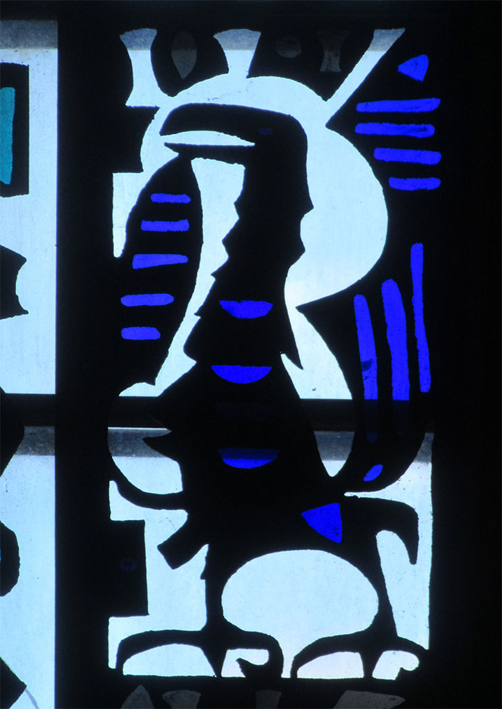 Close-up of stained-glass panel showing a stylized dark bird-like figure with bold blue accents against a bright white backlit background.