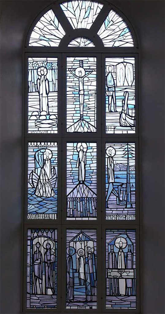 Tall stained-glass window with nine blue-toned panels depicting haloed biblical figures, crucifixion, gatherings, and scenes by water.