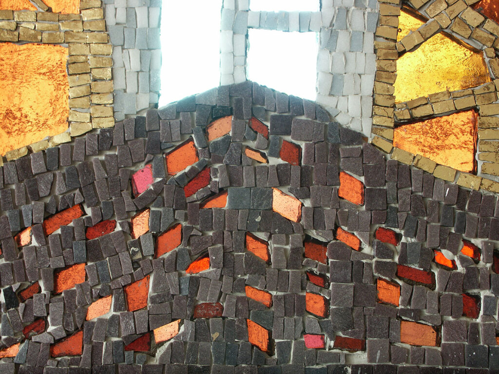 Colourful mosaic of small dark tiles mixed with orange and pink pieces, forming a textured hill shape beneath bright white and gold glass sections.