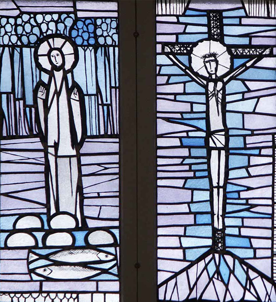 Stained-glass panels showing a haloed figure above loaves and fish beside another panel portraying a crucified figure among blue geometric shapes.