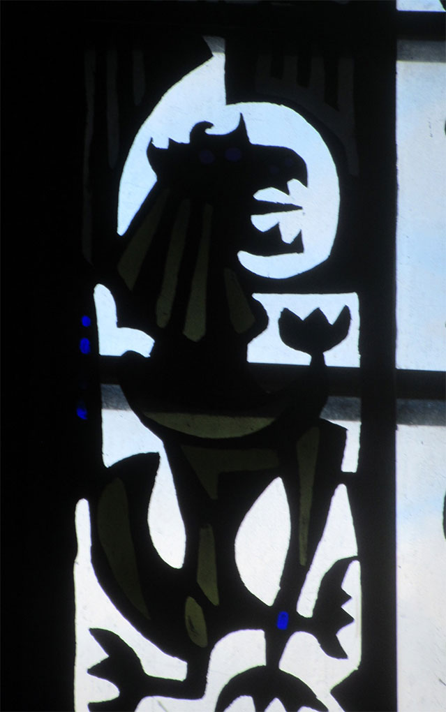 Stained-glass panel showing a stylized dark creature with sharp features and abstract shapes, set against a pale backlit background.