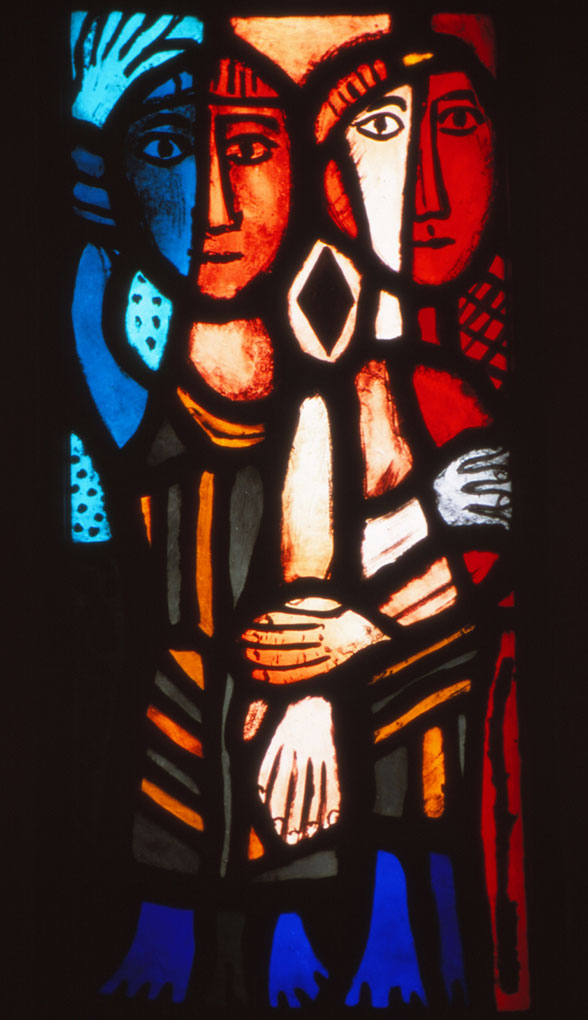 Stained-glass panel showing two stylized figures in vivid blue, red, and orange tones, their arms intertwined in bold black outlines.