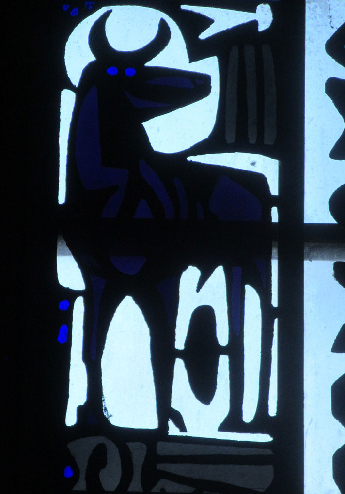 Stained-glass panel featuring a stylized blue-and-white animal figure with abstract shapes and patterns set against a softly glowing background.