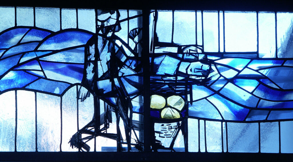 Blue-toned stained glass window depicting abstract figures and flowing wave-like shapes with bright highlights and textured glass sections.