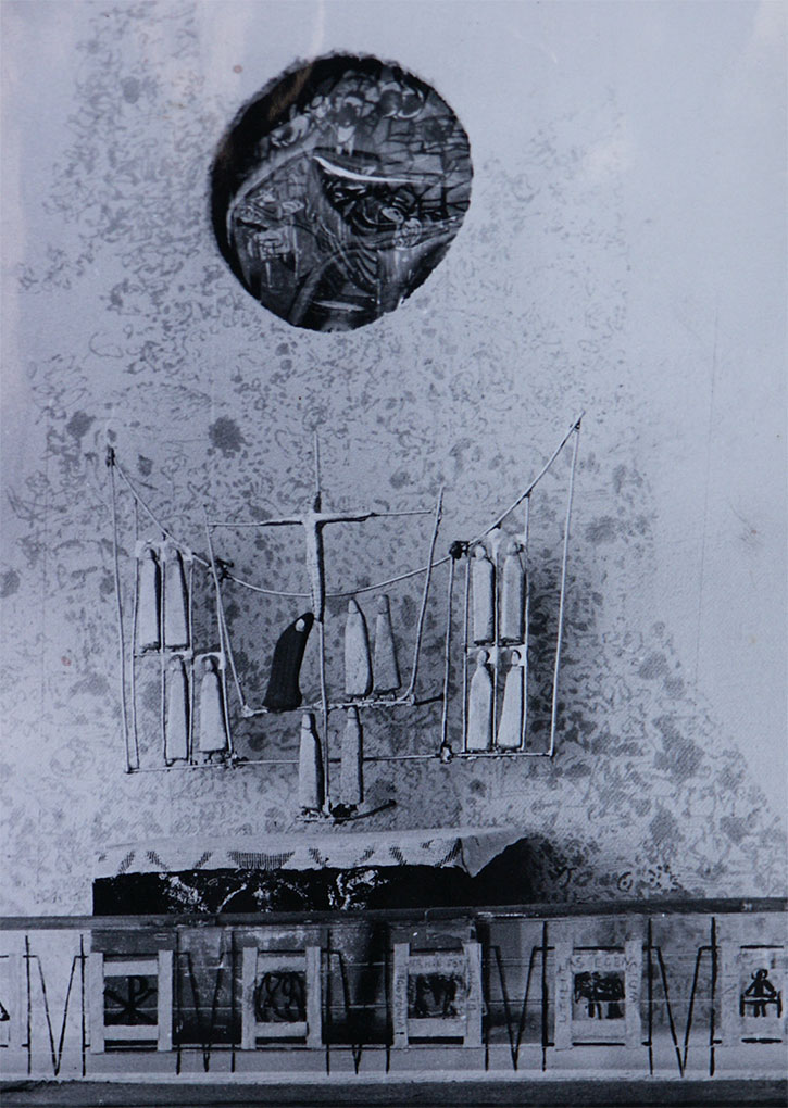 Black-and-white photo of a church altar model with a stylized crucifix and figures, set against a textured wall with a circular artwork above.