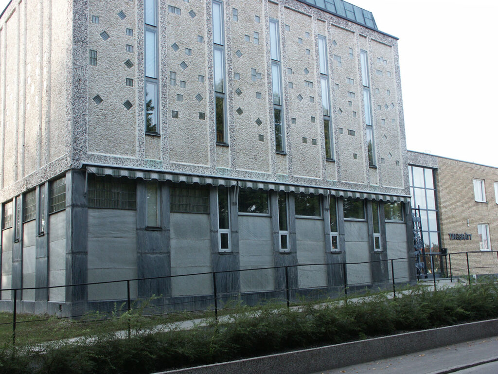 Side view of a textured concrete and glass courthouse building with tall narrow windows and geometric wall details.