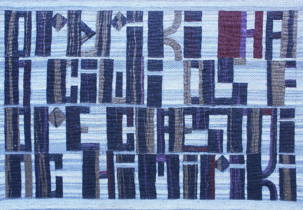 Dense tapestry of geometric letter shapes in blue and gray hues forming abstract text across a light fabric.