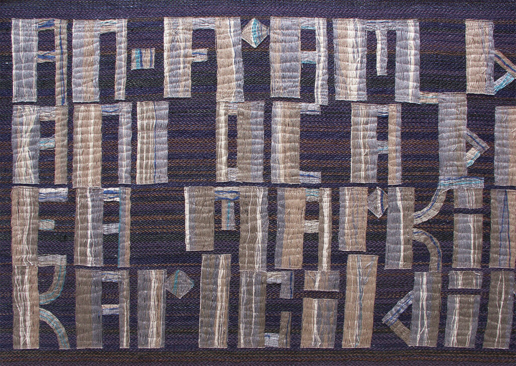 Woven panel of pale block-style letters forming abstract text bands across a dark blue-brown textile.