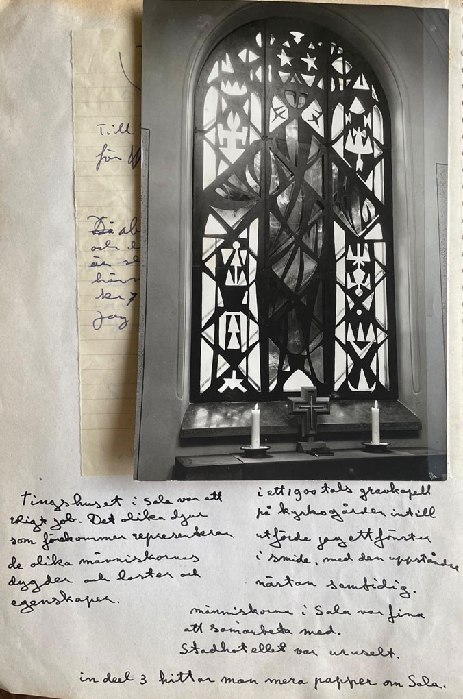 Black-and-white photo of an arched stained-glass window placed on handwritten notes, with two candles and a small cross at the bottom.