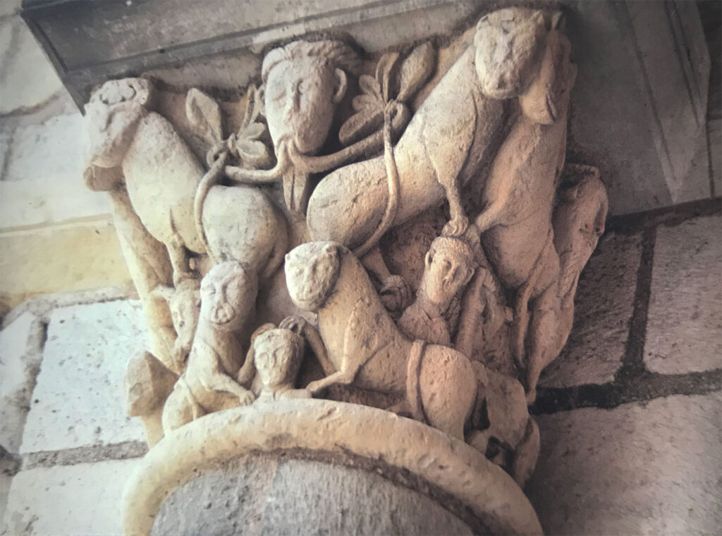 Weathered stone capital carved with intertwined human figures, animals, and foliage in a dense, expressive medieval sculptural scene.